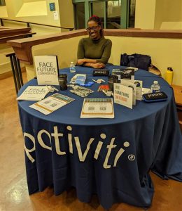 Cali Luke sits at a table with information related to her company, Protiviti, at a recruiting event.