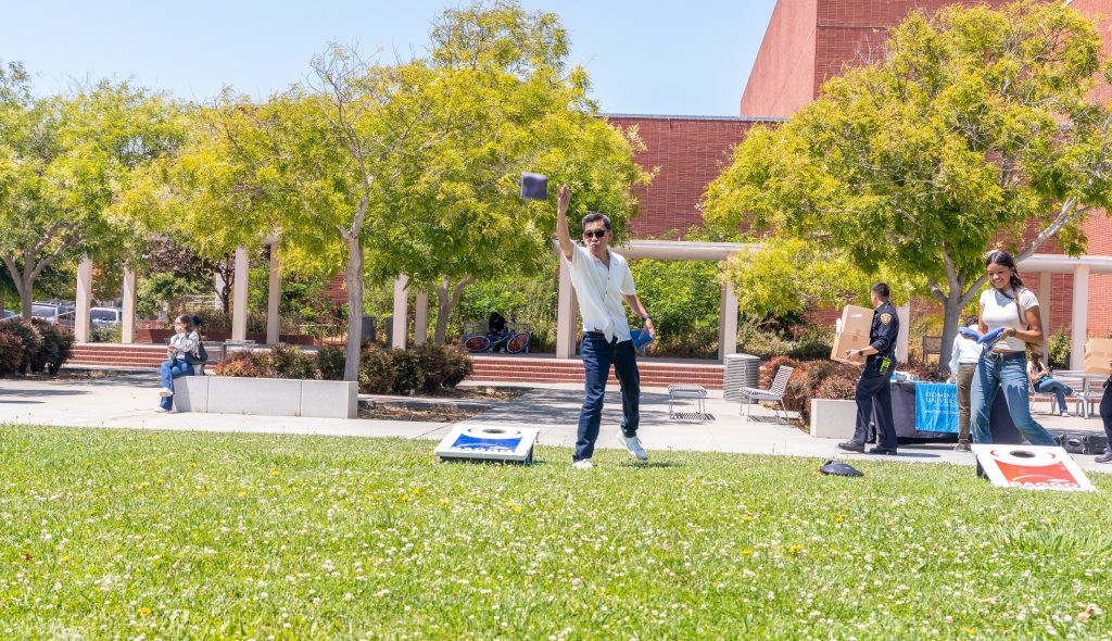 A member of the community tosses a bean bag while playing cornhole at the RP Scholar Celebration on August 3, 2024.
