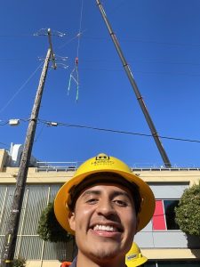 Jose Barrios wears a Herrero Builders hard hat while taking a selfie at a work site 