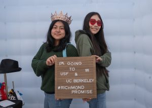 A pair of new Richmond Promise Scholars holds a sign that says "I'm Going to USF & UC Berkeley - #RichmondPromise" at RP's 2025 Scholar Celebration.