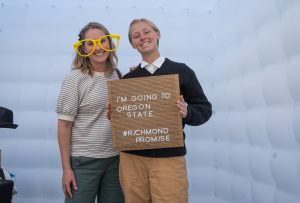 A new Richmond Promise Scholar poses with another attendee and holds a sign that says "I'm Going to Oregon State - #RichmondPromise" at RP's 2025 Scholar Celebration.