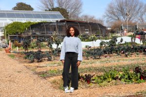 Bailey Ward poses for a photo in front of a row of vegetables on Urban Tilth's farm in North Richmond