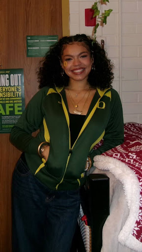 Photo of Jisselle Rodriguez standing in a dorm room wearing a University of Oregon sweatshirt.